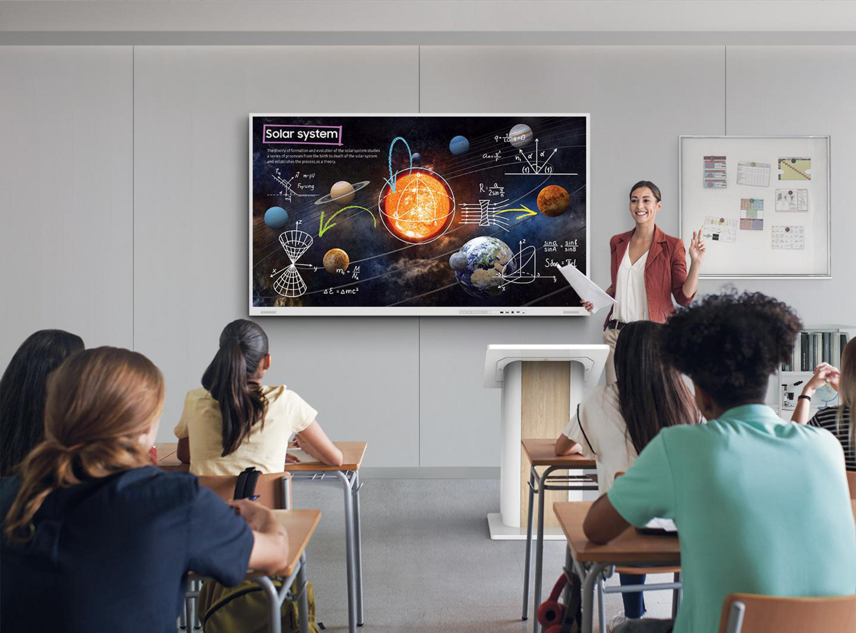 Insegnante accanto a grande schermo con grafico del sistema solare, spiega a studenti attenti in un'aula luminosa.