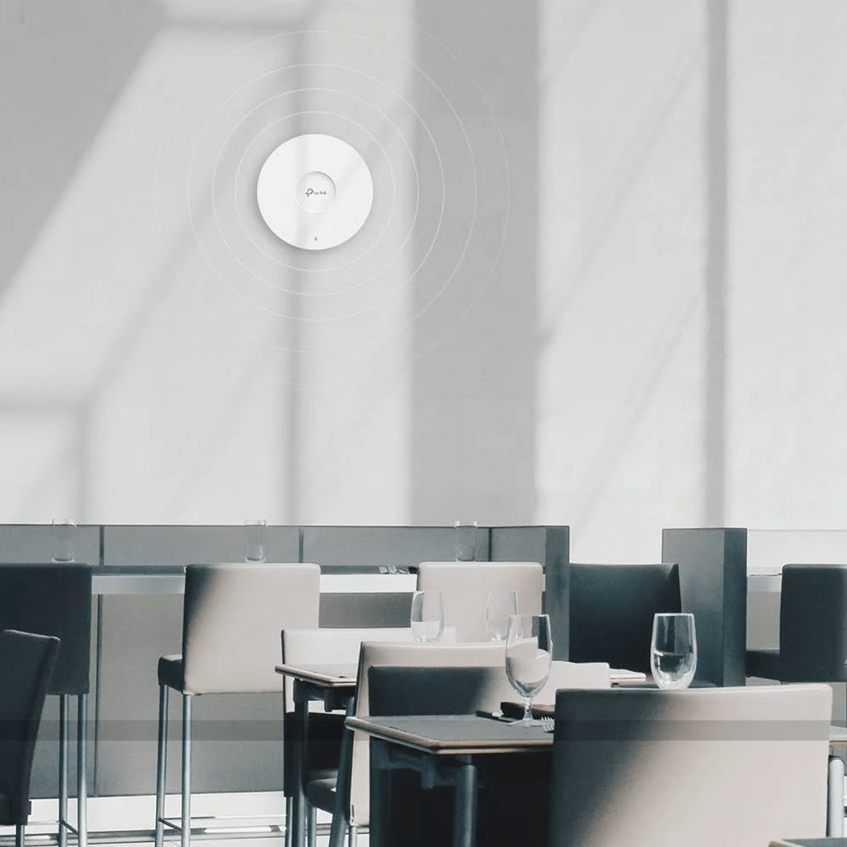 Un router Wi-Fi bianco su una parete in un ristorante con tavoli e sedie.