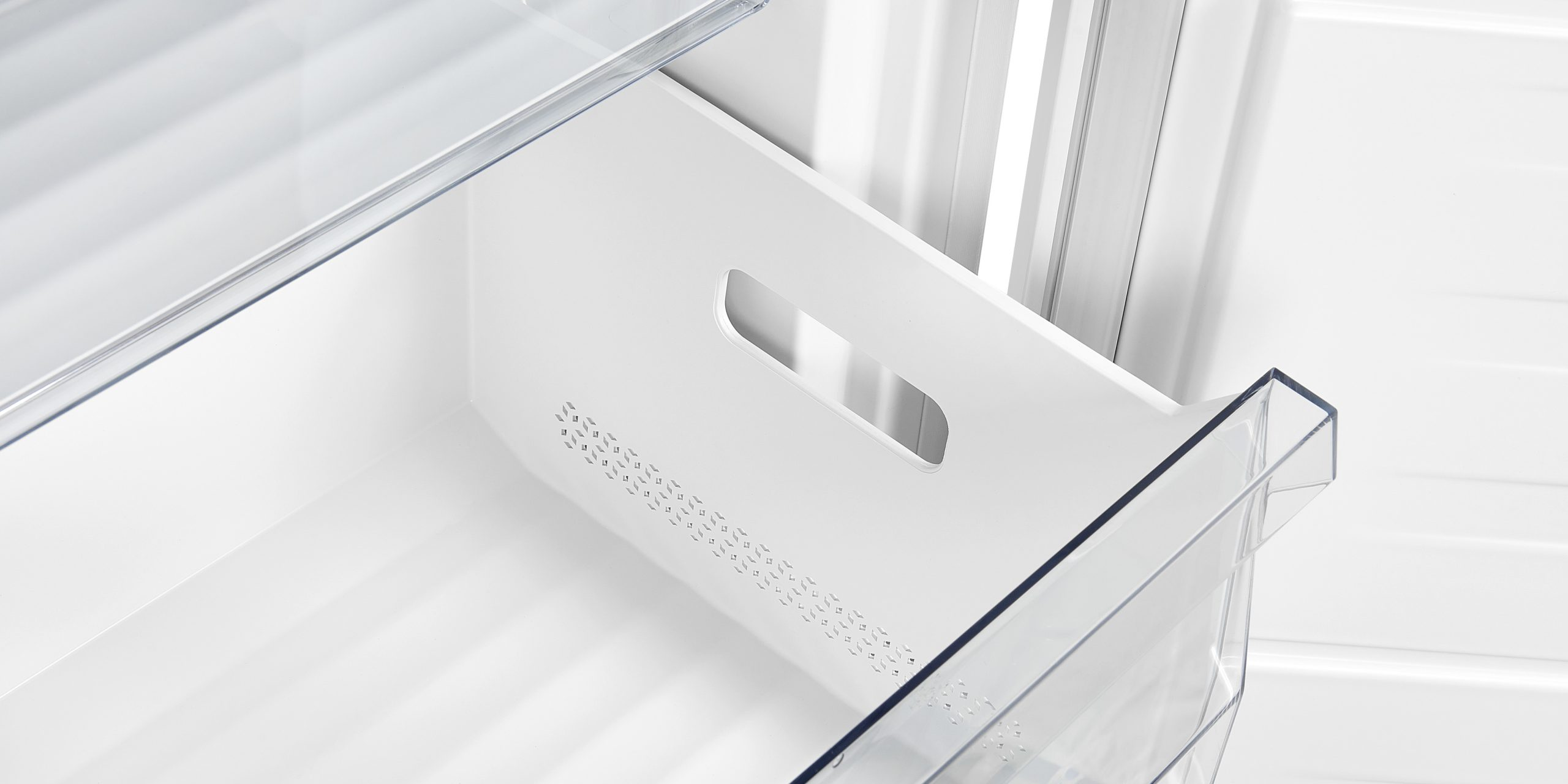 Un cajón verdulero de refrigerador blanco y vacío con tirador integrado.