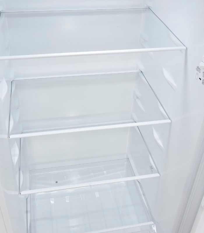 Ein Blick in einen leeren, weißen Kühlschrank mit drei Glasböden.