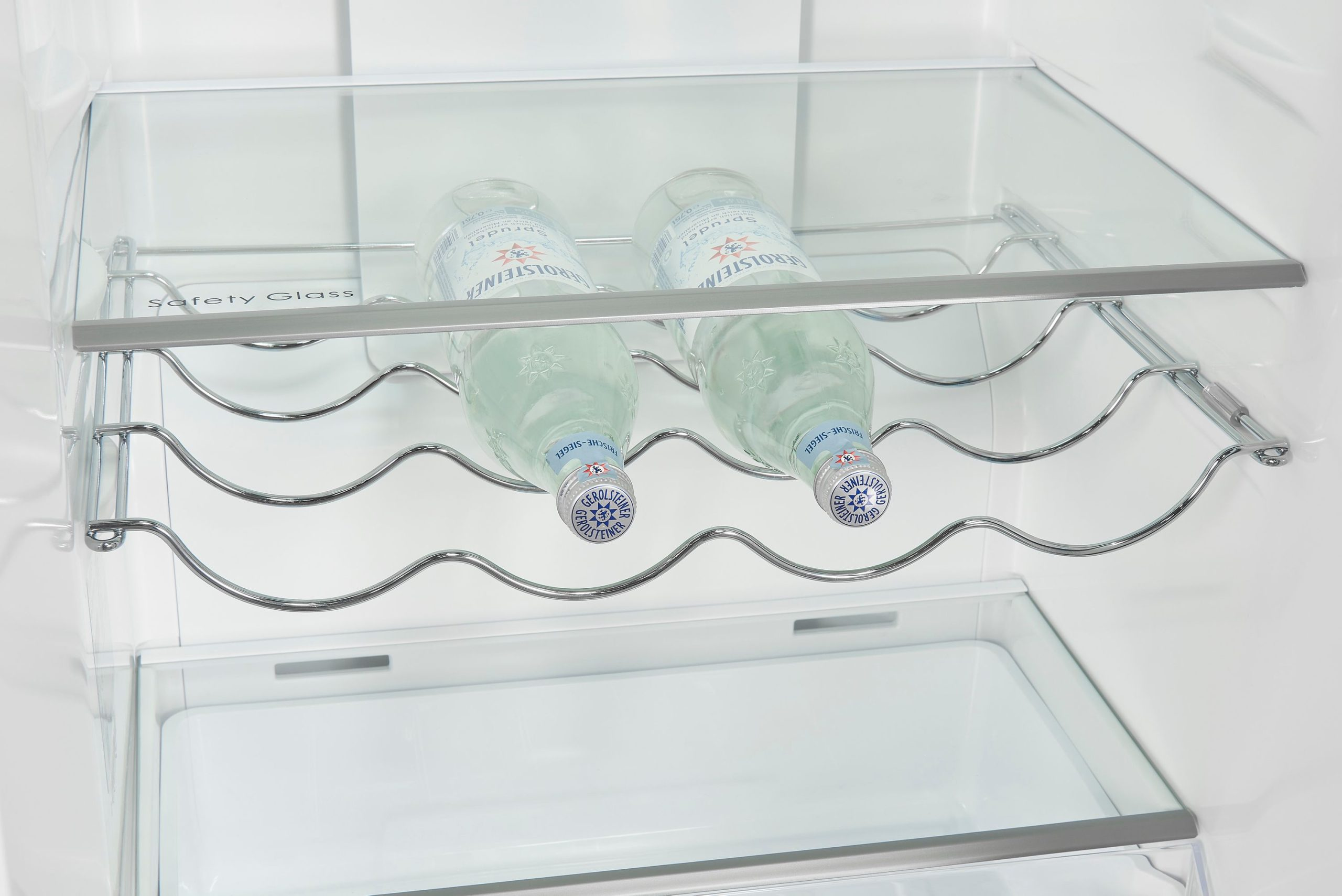 Zwei Glasflaschen liegen auf einer verchromten Metallhalterung im Kühlschrank.
