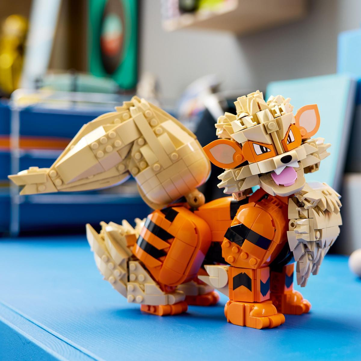 Mavi masa üzerinde büyük kabarık kuyruklu, turuncu ve bej renkli kaplana benzer bir Lego modeli.