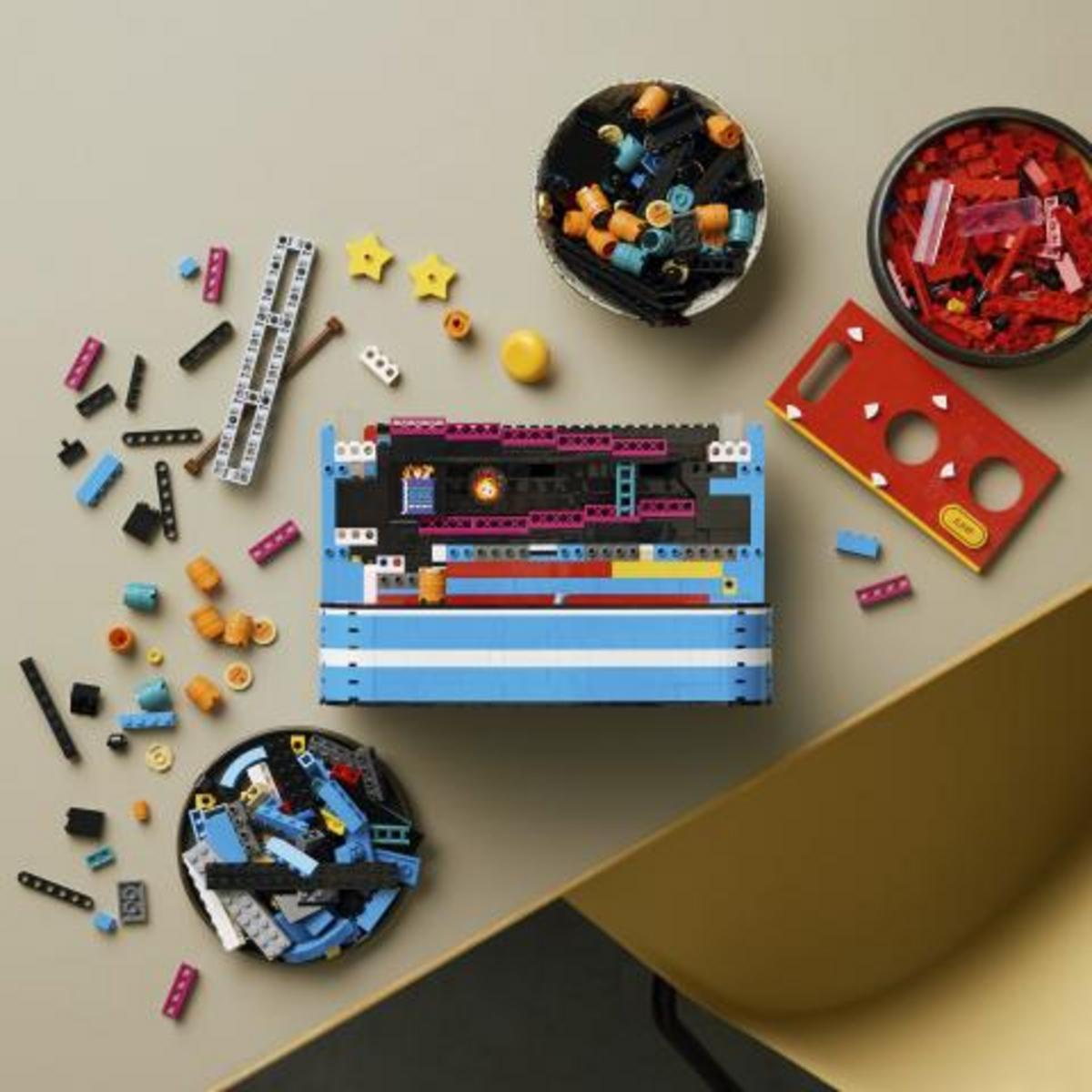 Bovenaanzicht van kleurrijke Lego-blokjes, stukjes en twee kommen vol stenen op een tafel.
