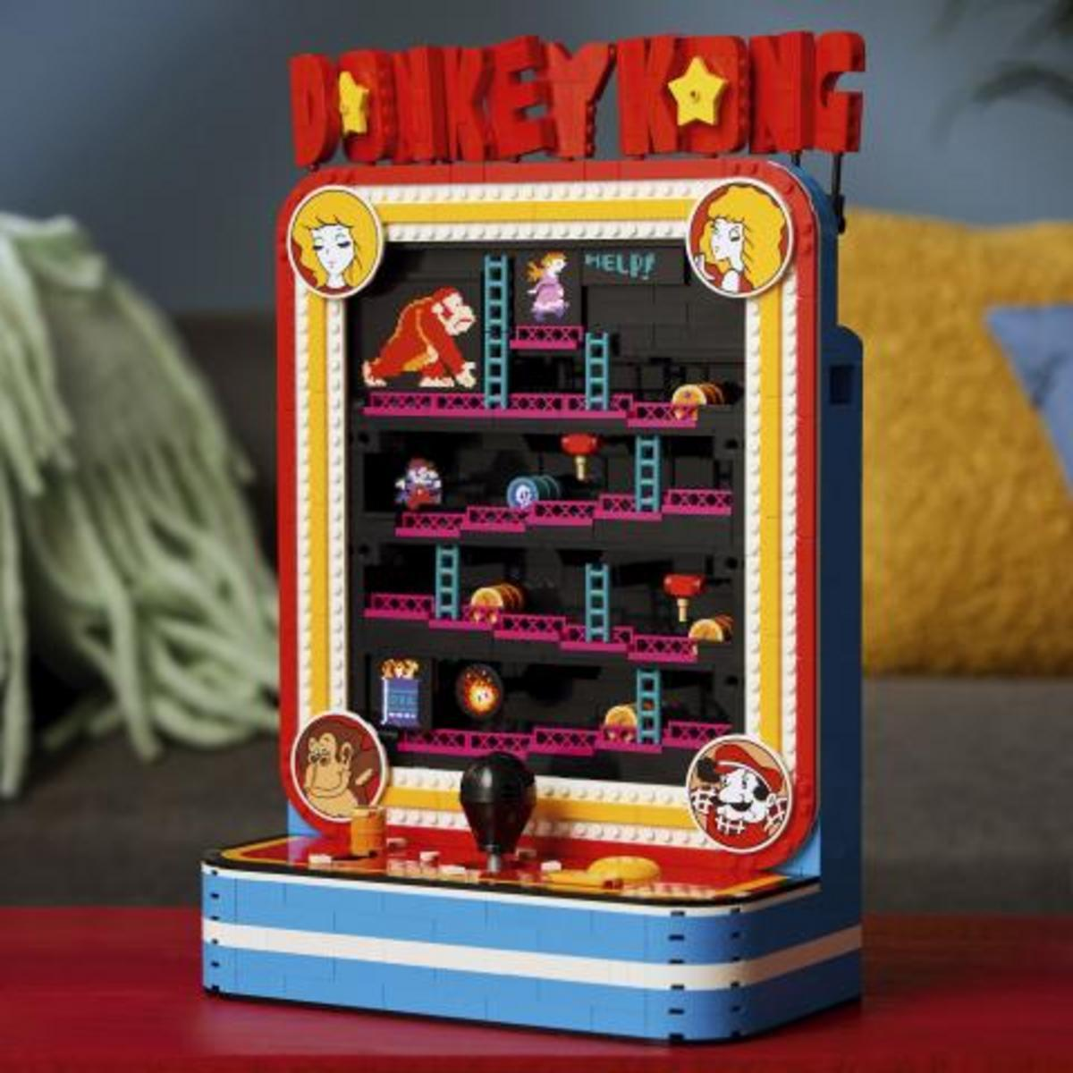 Een Lego Donkey Kong arcadekast met figuren, ladders en tonnen op een tafel.