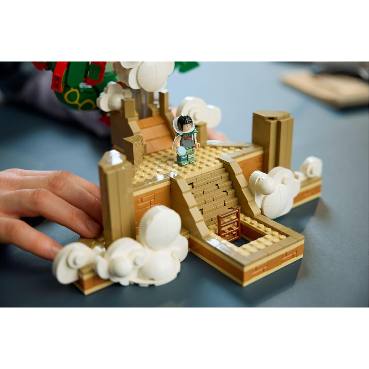 Beyaz bulutlarla çevrili inşa edilebilir kale merdivenlerinde duran Lego figürü.