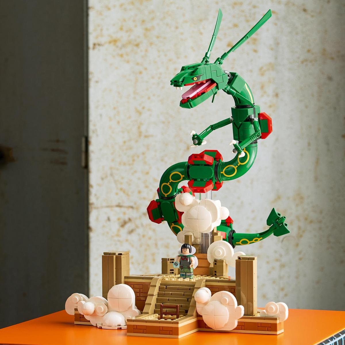 Taş kaide üzerinde miniatür figür ve beyaz Lego bulutlarıyla yeşil ejderha Rayquaza'n ın Lego modeli.