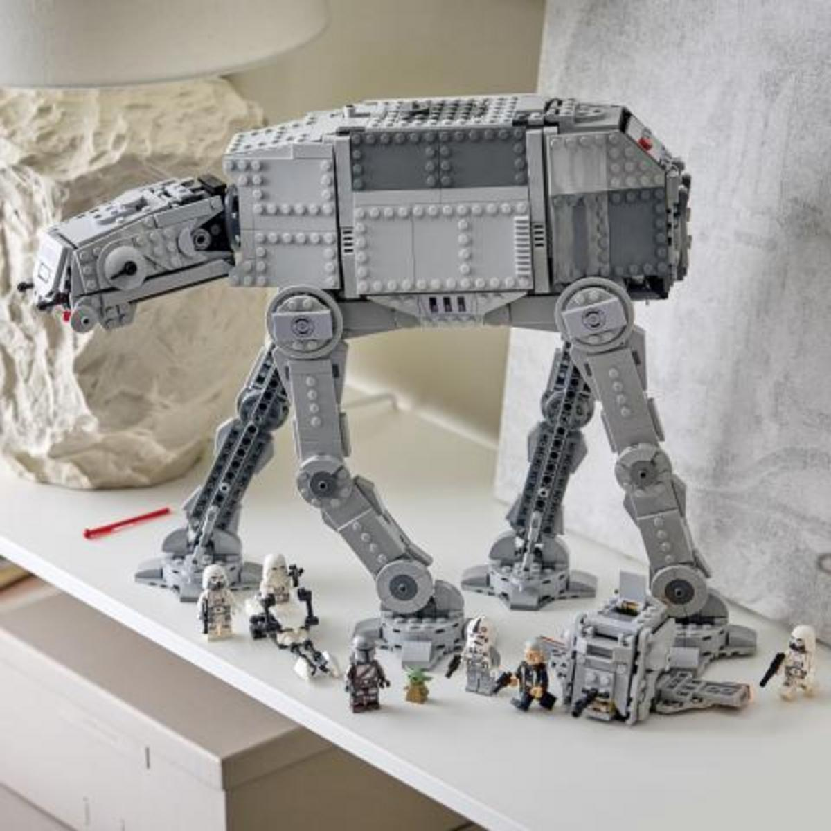 Un gran modelo Lego AT-AT Walker se encuentra en una superficie blanca con varias minifiguras.