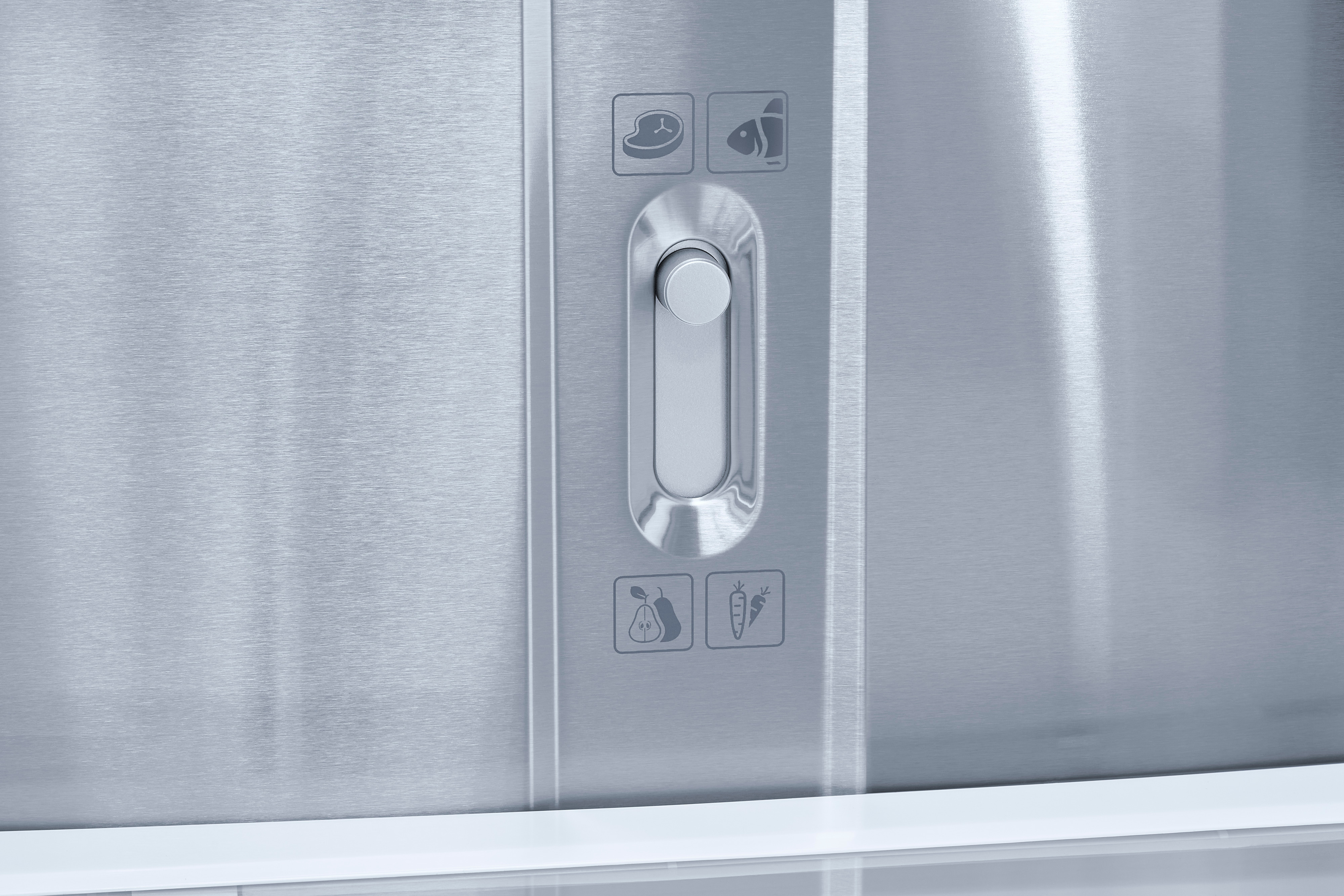 Nahaufnahme einer Edelstahlschublade im Kühlschrank mit Schieberegler und Lebensmittelsymbolen.