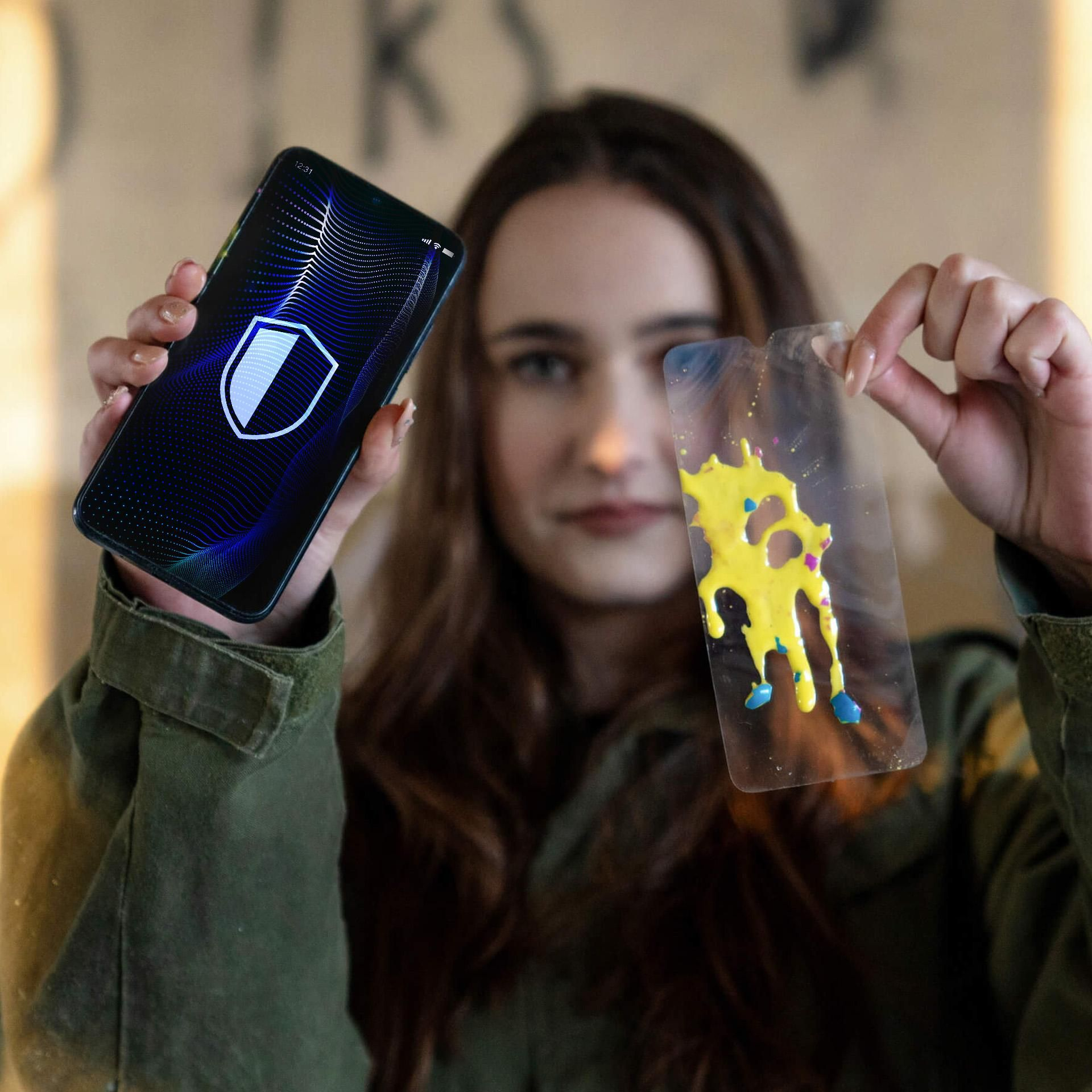 Una donna regge uno smartphone con icona scudo e una pellicola trasparente con vernice gialla e blu.