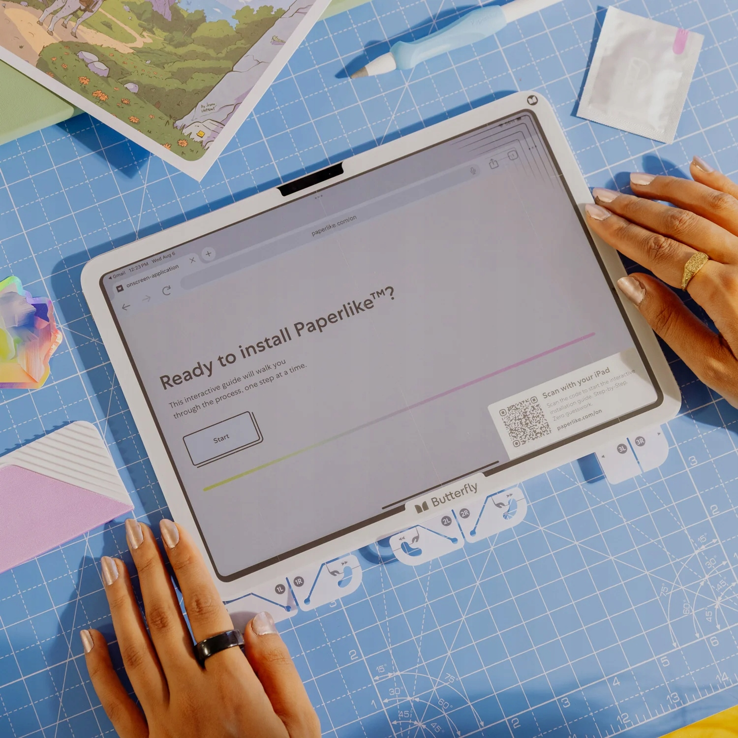 Un tablet con una guida di installazione su un tappetino blu, circondato da mani e strumenti.
