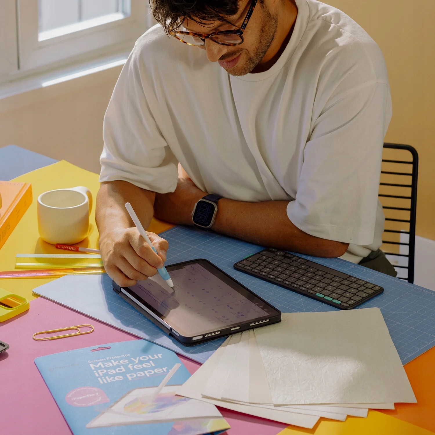 Un uomo con una camicia bianca a una scrivania colorata disegna su un tablet con uno stilo.