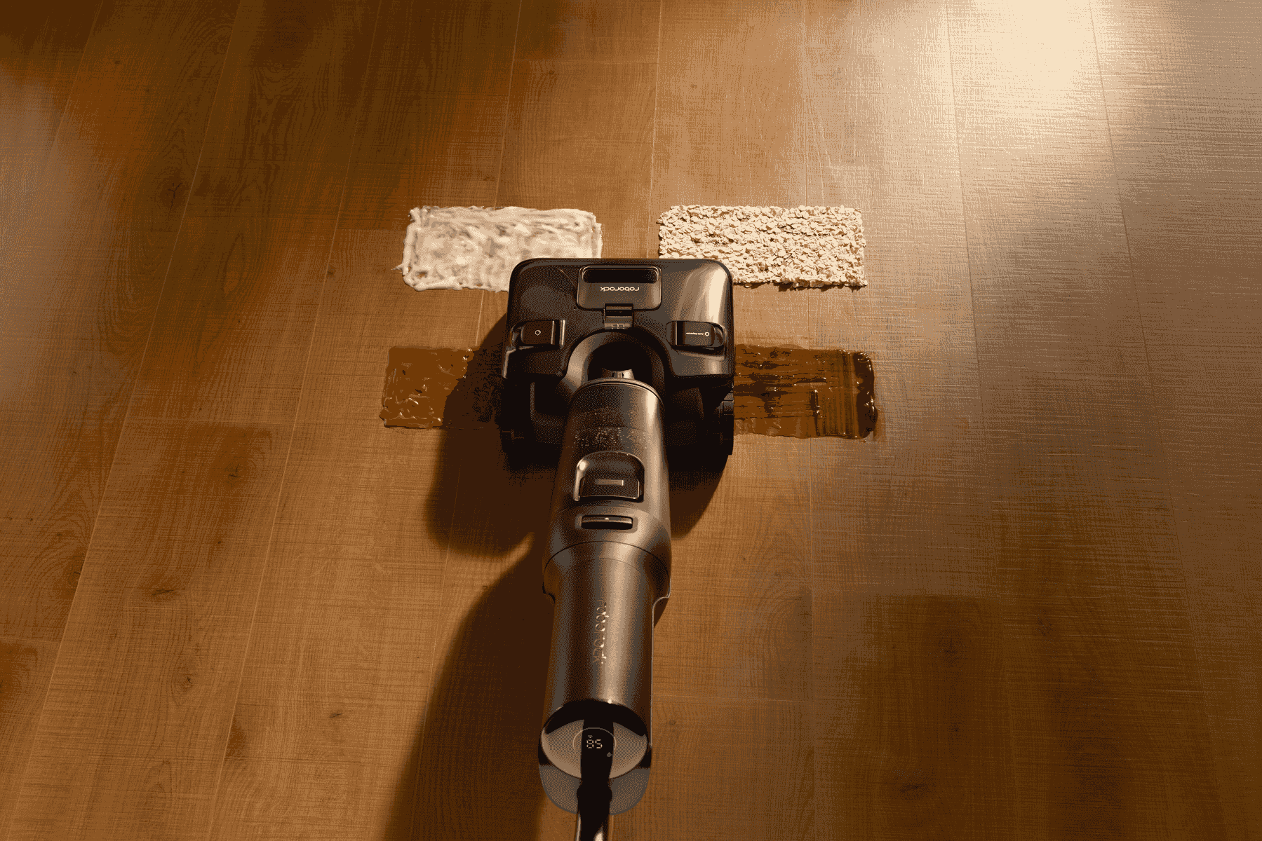 Una aspiradora en seco y húmedo limpia un derrame marrón y avena en un piso de madera.