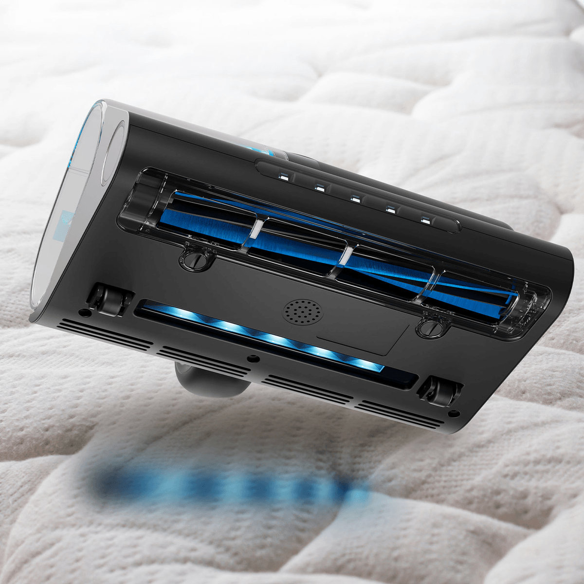 Un aspirapolvere portatile nero con spazzola a luce UV blu pulisce un letto in tessuto chiaro.