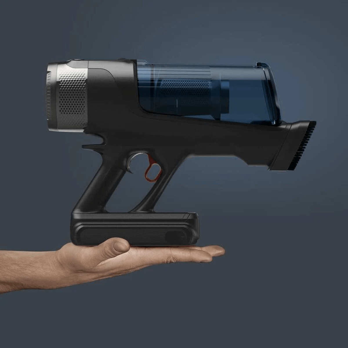 Una mano regge un moderno aspirapolvere portatile nero con serbatoio blu su sfondo grigio.