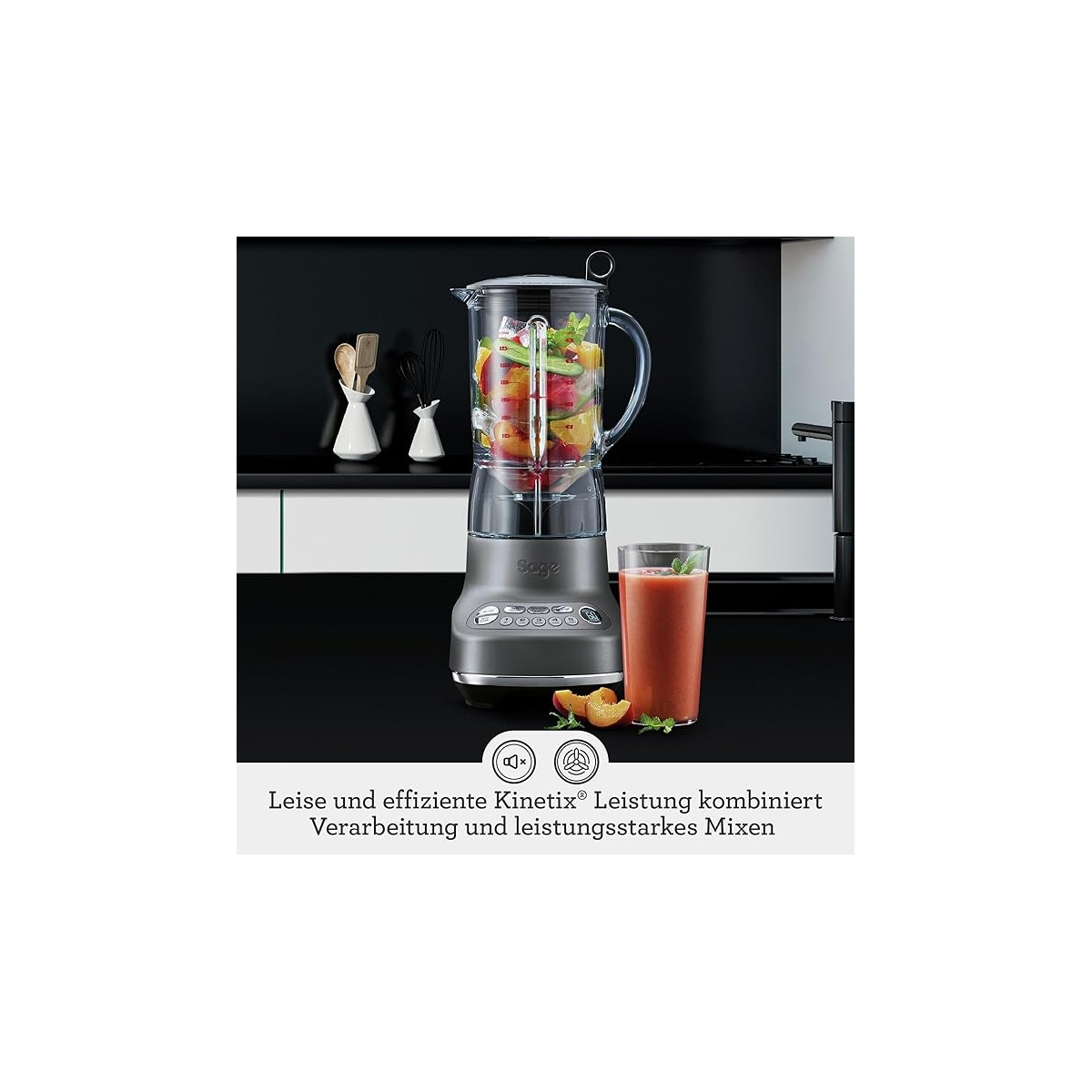 Un frullatore grigio con una caraffa piena e un bicchiere di smoothie si trova in una cucina moderna.