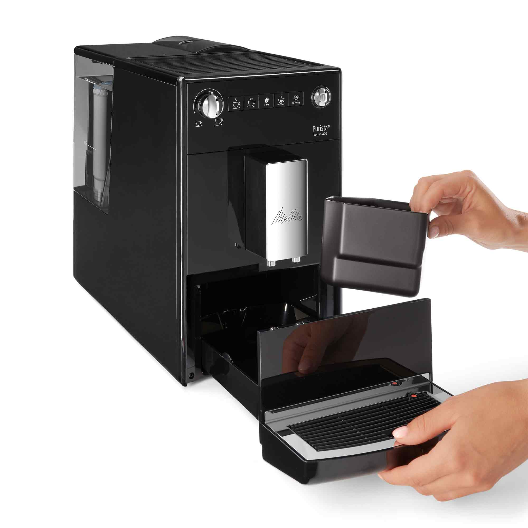 Eine schwarze Melitta Purista Kaffeemaschine mit Händen, die das Fach und die Abtropfschale öffnen.