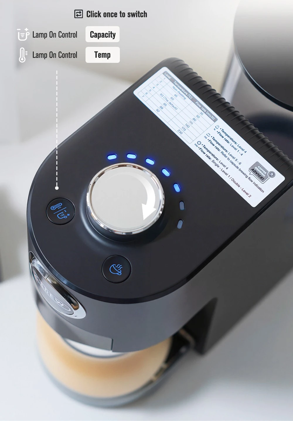 Vista dall'alto di una macchina da caffè nera con manopola argentata, indicatori LED blu e adesivo informativo.