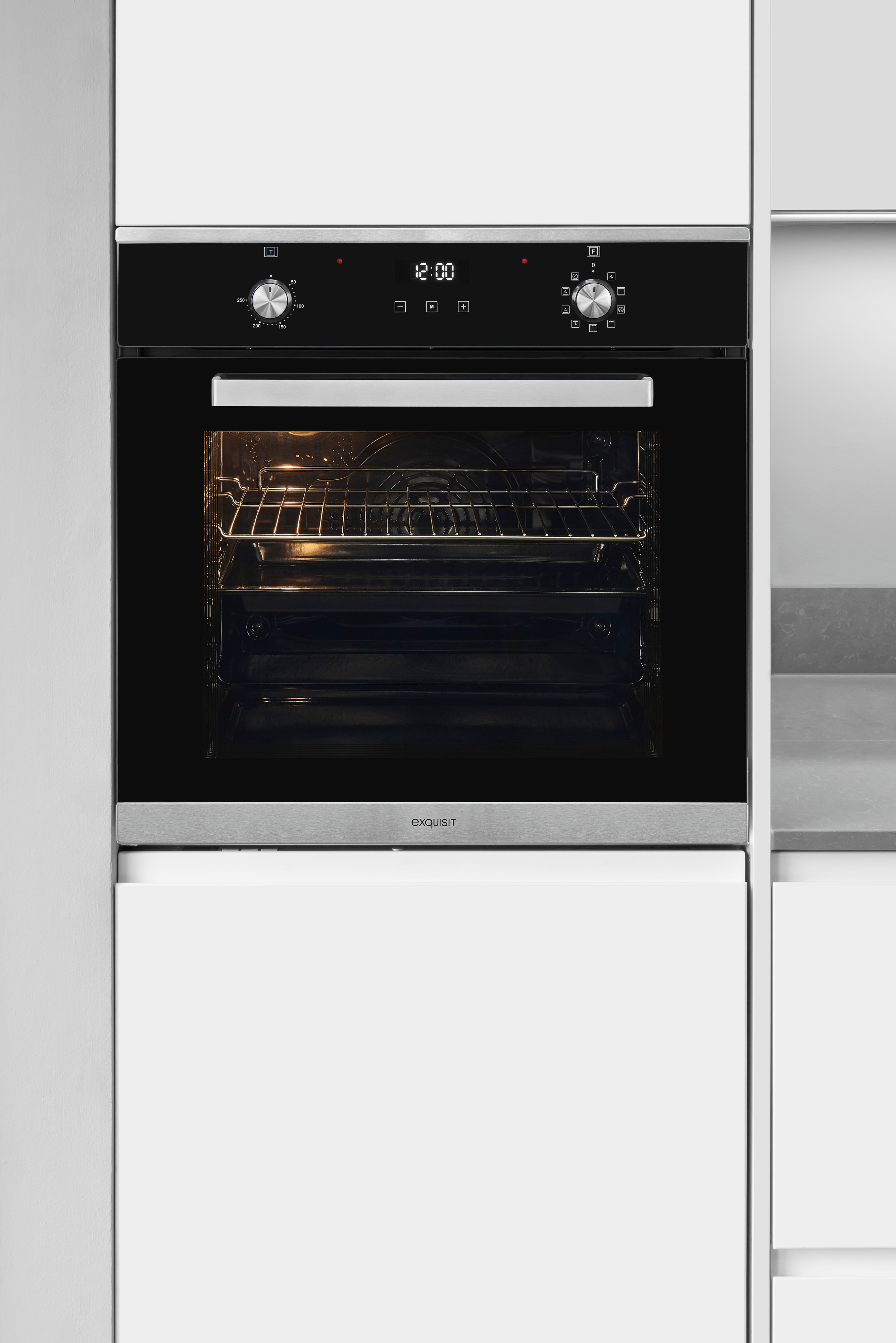 Un horno negro y de acero inoxidable empotrado con reloj digital a las 12:00 en un mueble de cocina blanco.