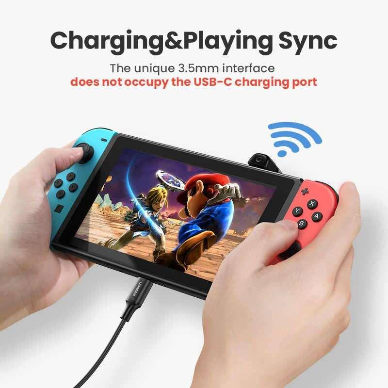 Mavi ve kırmızı Joy-Con'lu, şarj kablosu bağlı bir Nintendo Switch tutan kişi.