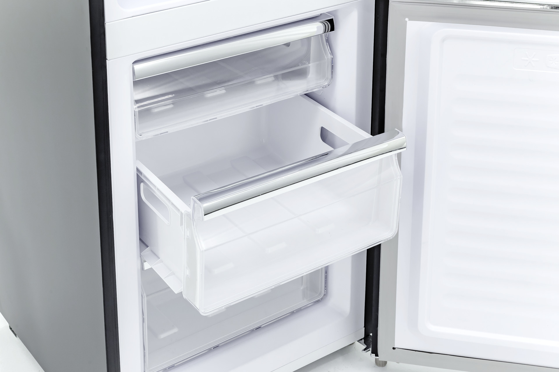 Offener Kühlschrank mit einer transparenten, herausgezogenen Schublade im Innenraum.