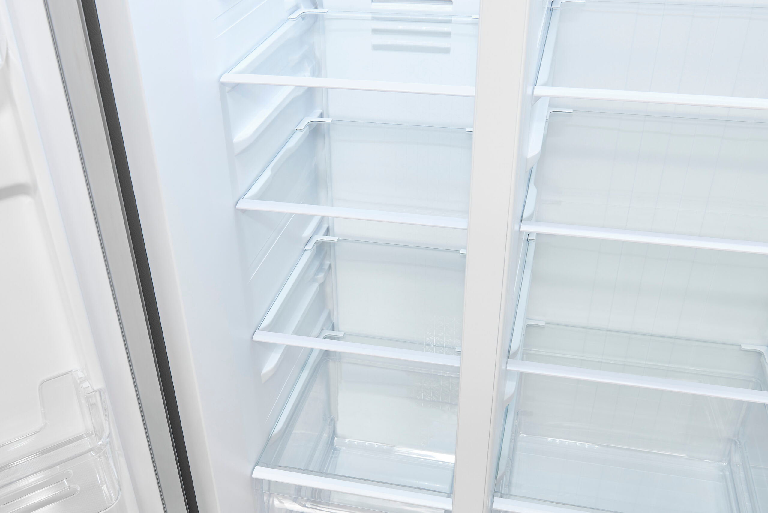 Das Innere eines leeren, sauberen weißen Haushaltskühlschranks mit Glasböden.