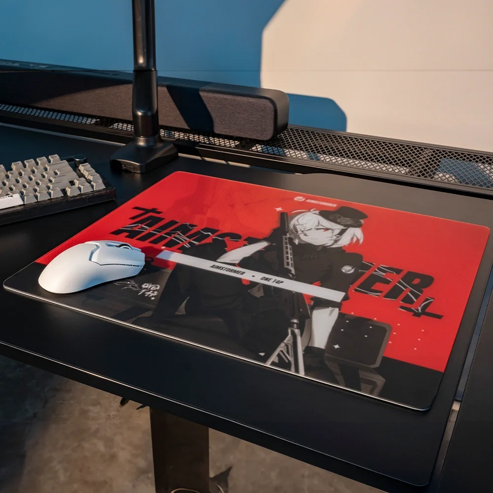 Siyah bir masada, kırmızı ve siyah anime mousepad üzerinde beyaz bir oyuncu faresi.