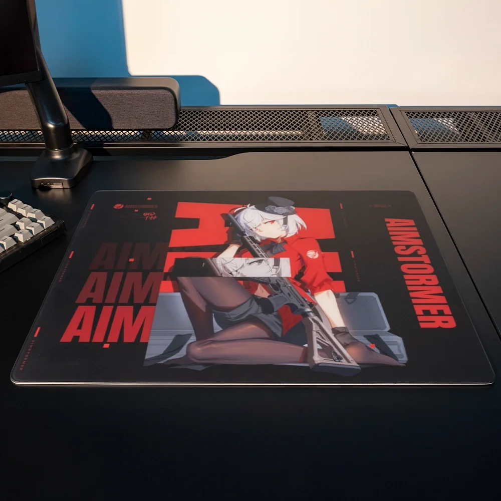 Tüfek tutan bir anime kız, kırmızı AIMSTORMER yazısı, klavye ve monitör standı olan siyah bir masa matı.