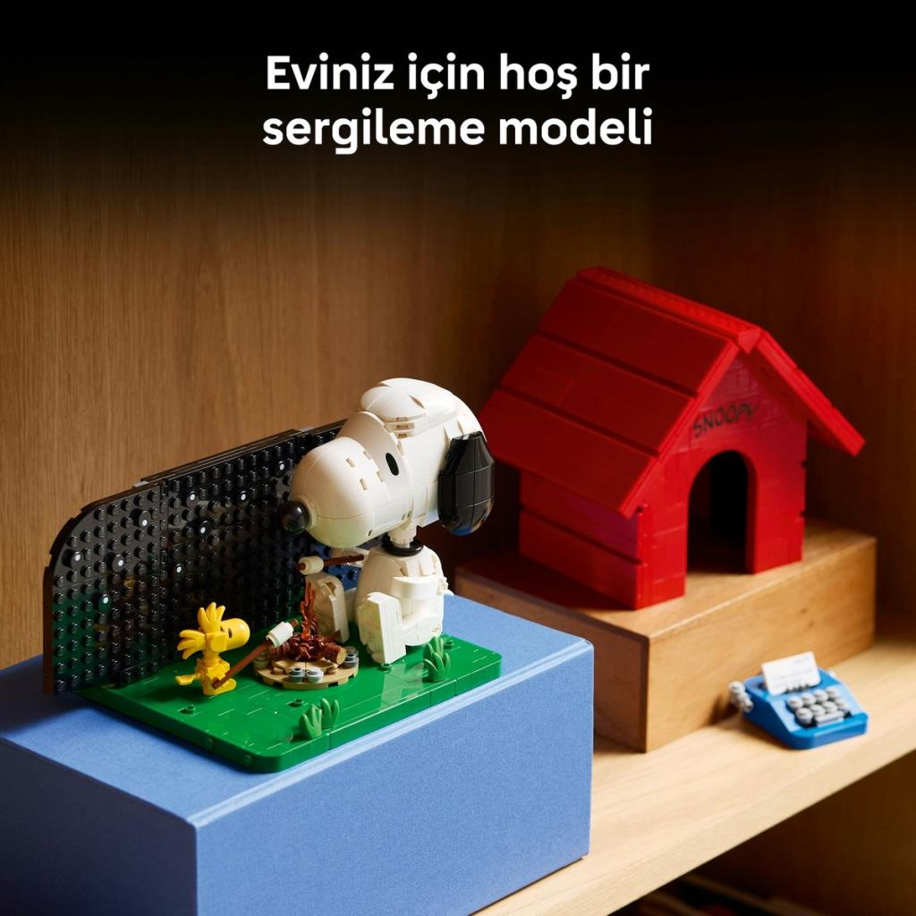 Kırmızı köpek kulübesi ve daktilonun yanında kamp ateşi başındaki Snoopy Lego modeli.
