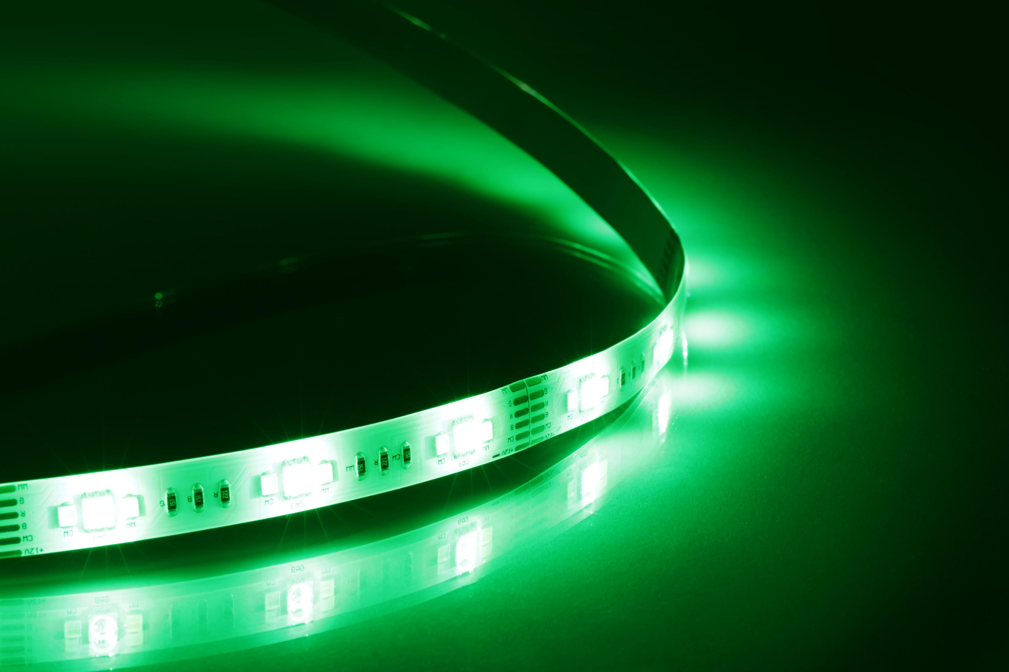 Ein heller, grüner LED-Streifen windet sich auf einer dunklen Oberfläche und wirft ein starkes grünes Licht ab.
