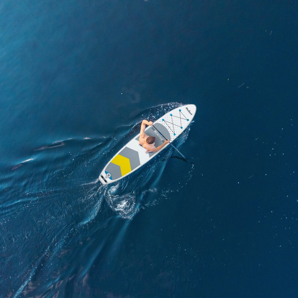 Vista dall'alto di una persona che fa paddleboard su acqua blu scuro.