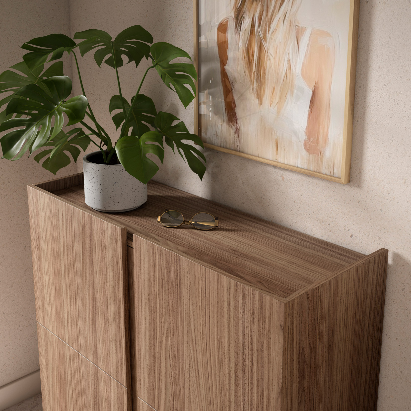 Mueble de madera con planta en maceta y gafas encima, además de un cuadro enmarcado.