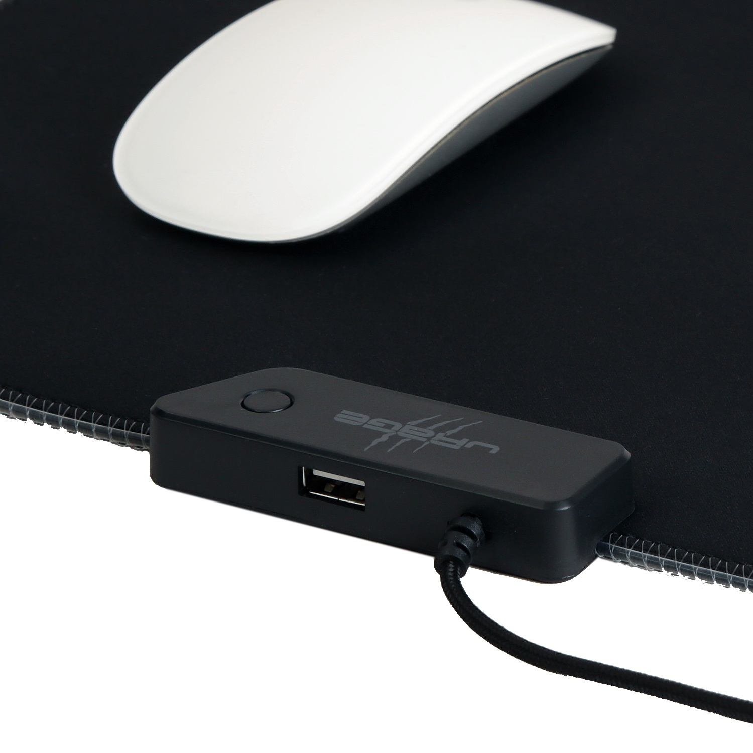 Eine weiße Computermaus liegt auf einem schwarzen Mauspad mit einem USB-Hub am unteren Rand.