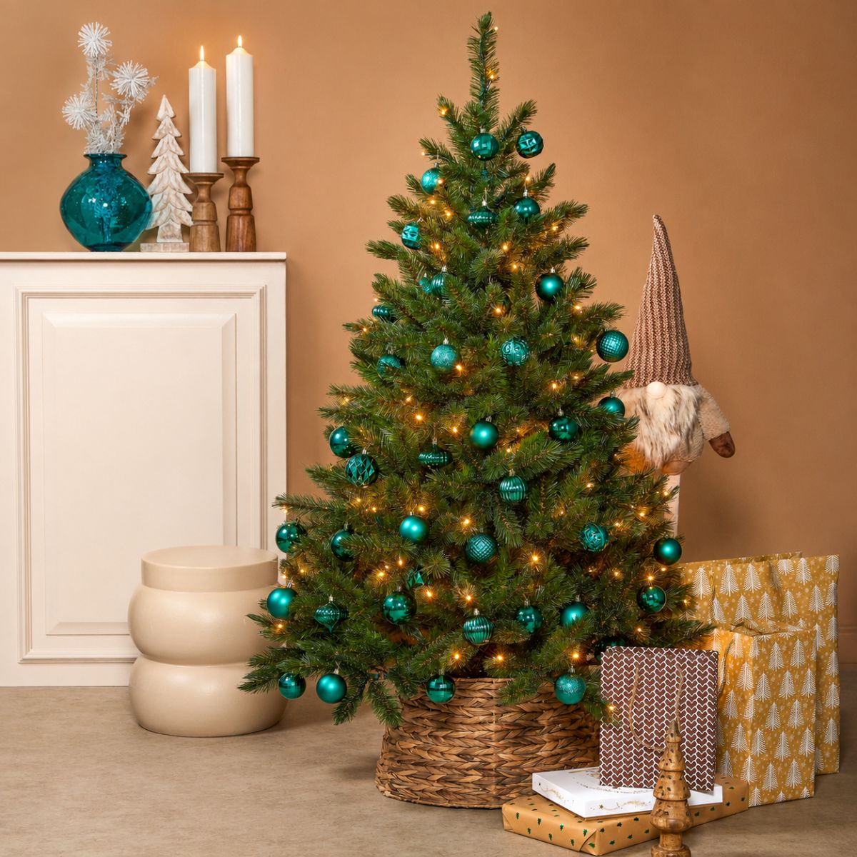 Un sapin de Noël décoré avec des boules bleues et des lumières dans un panier près de cadeaux.