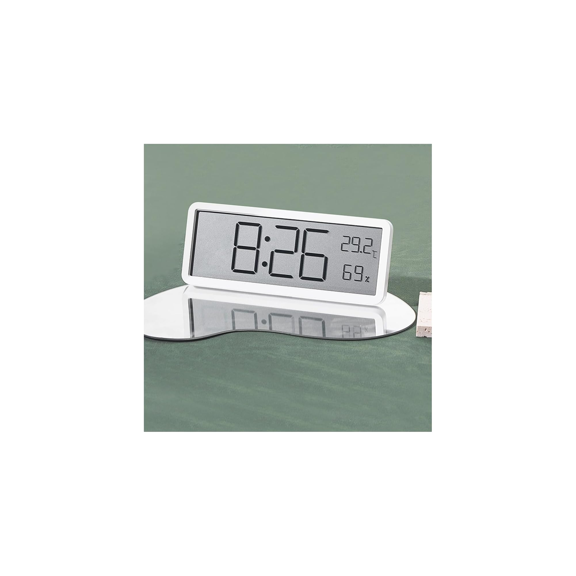 Eine weiße Digitaluhr mit Temperatur- und Feuchtigkeitsanzeige steht auf einem Spiegel.