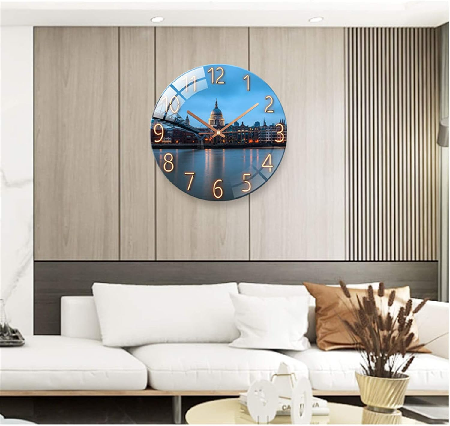 Eine große Wanduhr mit einer nächtlichen Stadtlandschaft auf dem Zifferblatt hängt über einem modernen weißen Sofa.