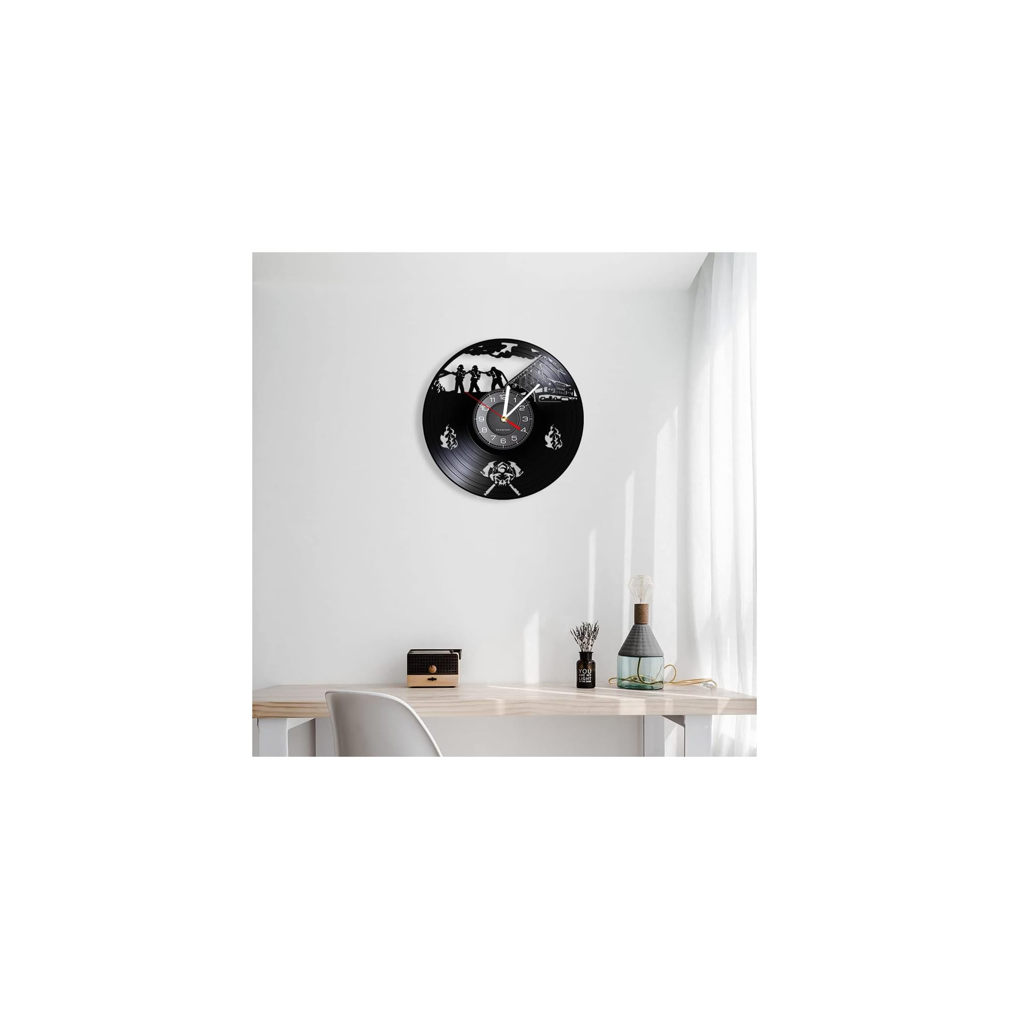 Eine schwarze Vinyluhr mit Feuerwehrmotiv hängt an einer weißen Wand über einem Holztisch.