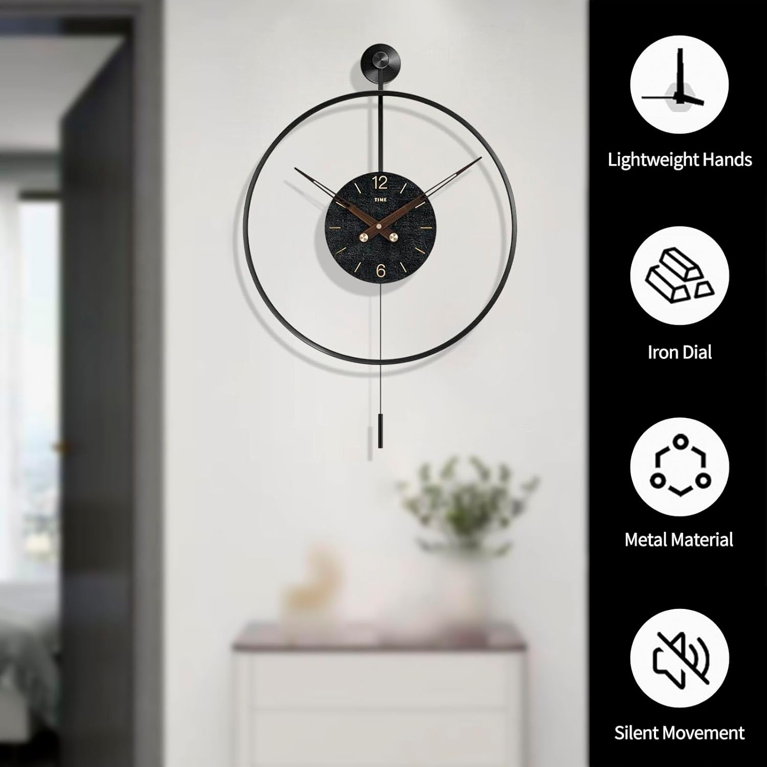 Moderne schwarze Wanduhr mit großem Ring und Pendel, an weißer Wand über Kommode hängend.