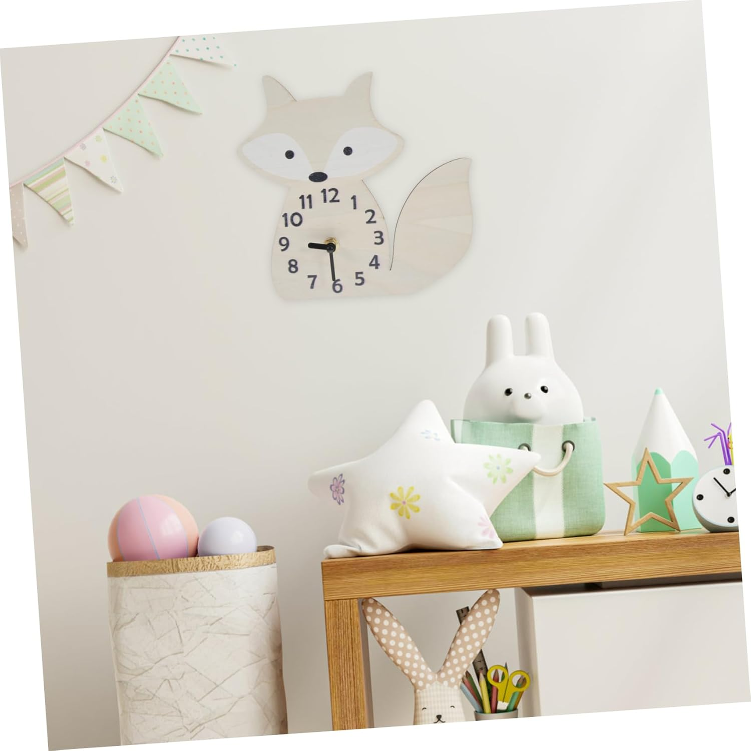 Kinderzimmer mit fuchsförmiger Uhr, Sternkissen, weißer Hasenlampe in grüner Tasche und Spielzeug auf einem Holzregal.