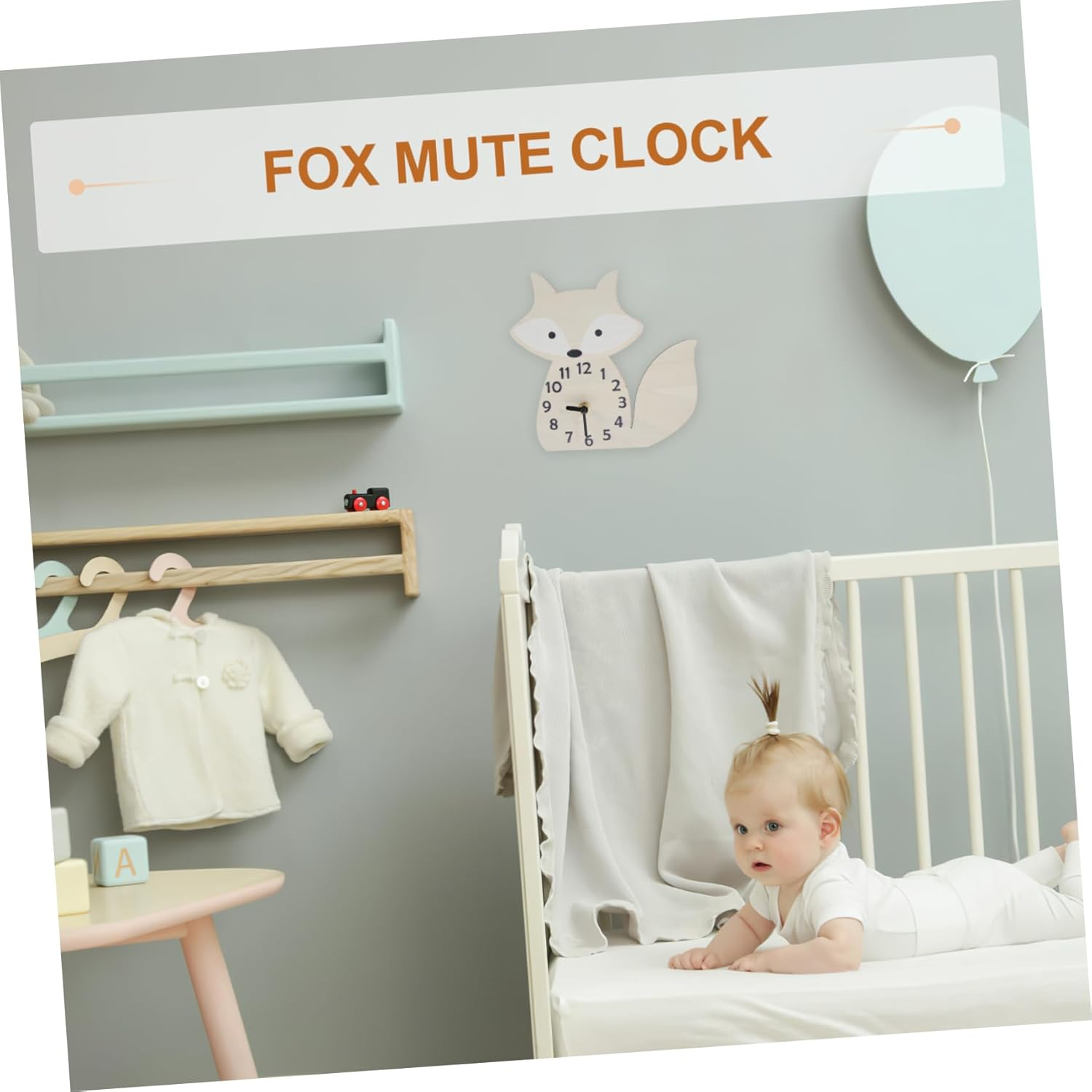 Ein Baby liegt auf einem Bett in einem grauen Kinderzimmer mit Fuchs-Wanduhr und hängendem Kleiderbügel.