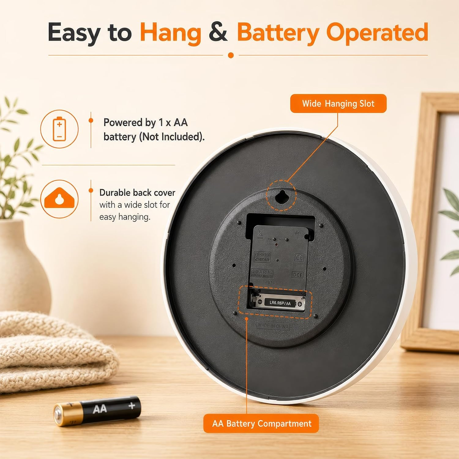Rückseite einer weißen Uhr mit Batteriefach und Aufhängeöse, daneben eine AA-Batterie auf einem Holztisch.