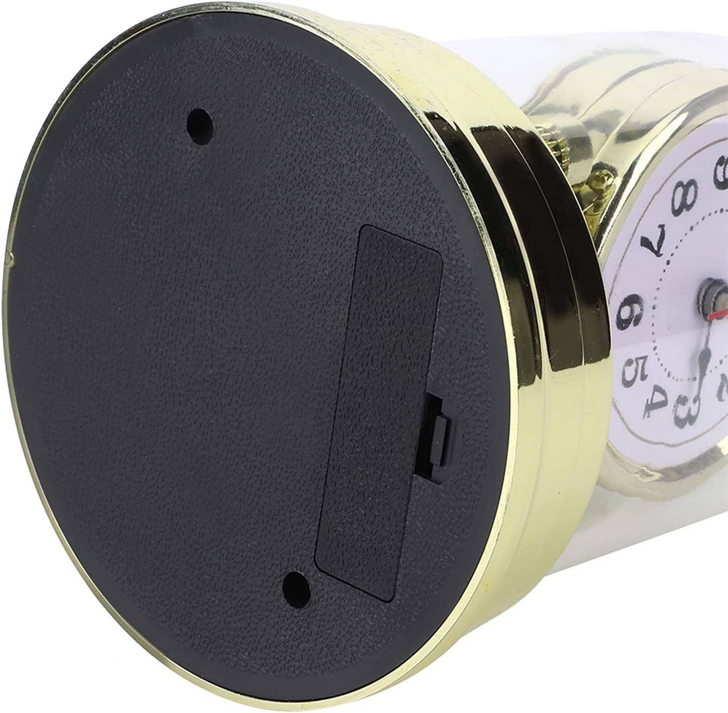 Unteransicht einer kleinen Uhr mit schwarzem Sockel, Batteriefach, zwei Schraublöchern und goldgerändertem weißem Zifferblatt.