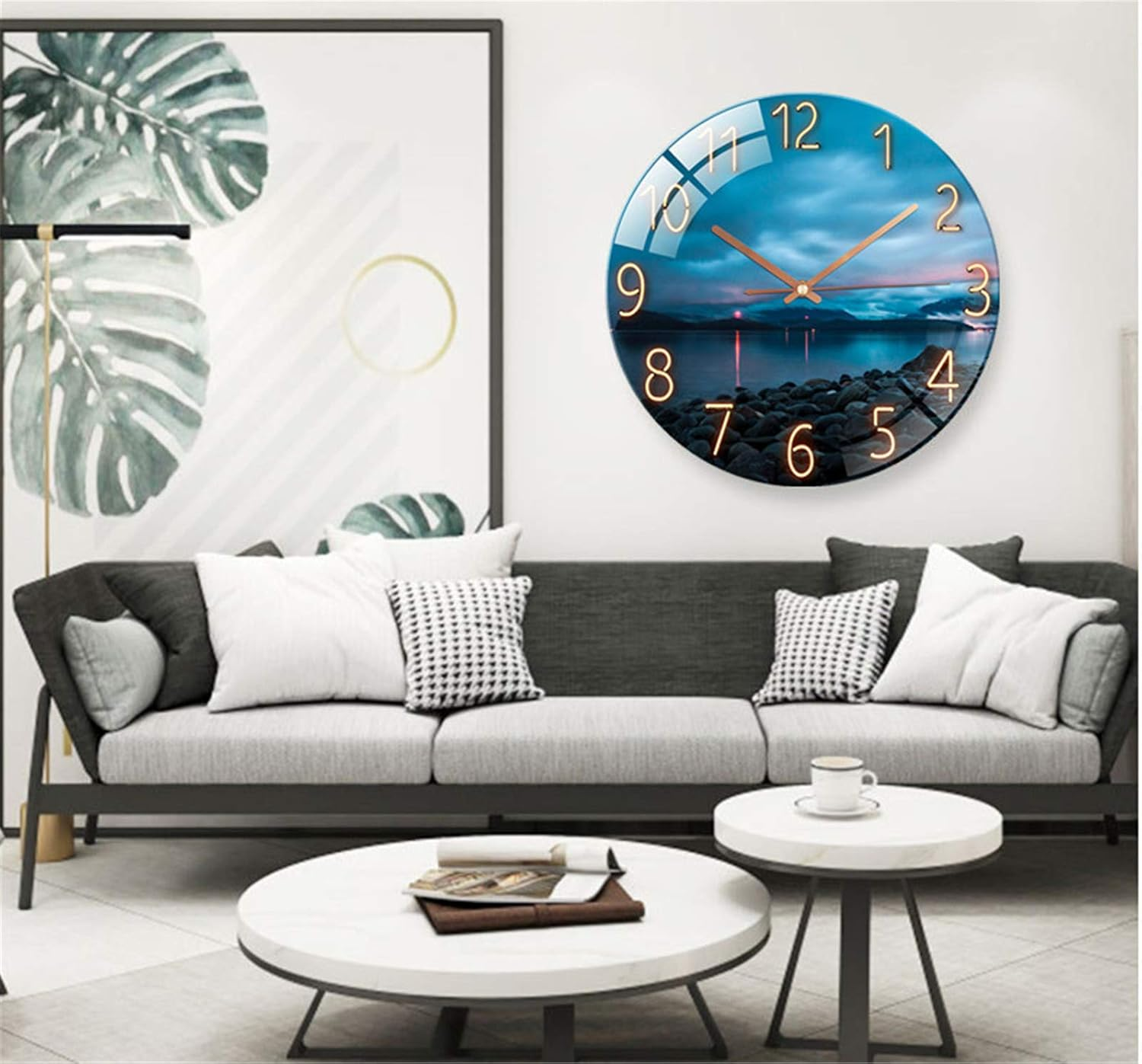 Wohnzimmer mit grauem Sofa, weißen Couchtischen und einer großen Wanduhr mit Landschaftsmotiv.