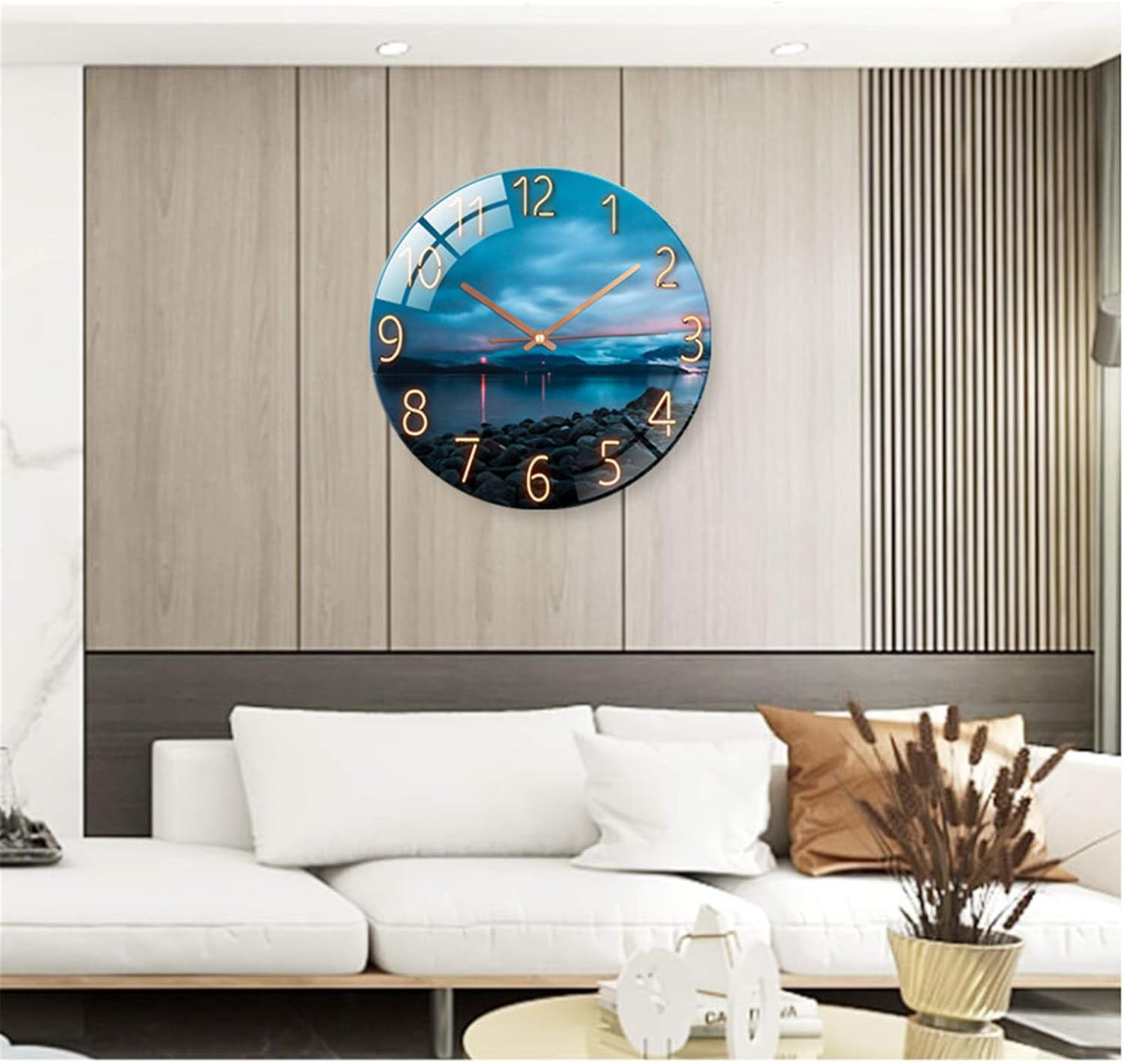 Eine runde Wanduhr mit Landschaftsmotiv hängt über einem weißen Sofa in einem modernen Zimmer.