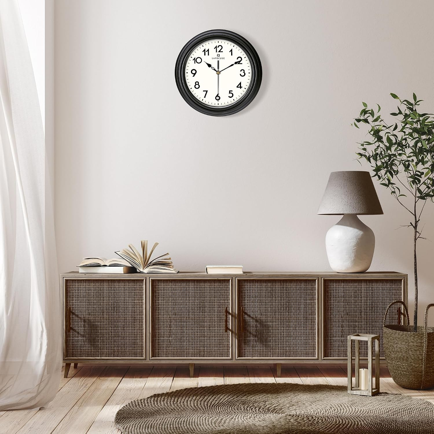 Wohnzimmer mit dunkler Wanduhr, Rattankonsole, Lampe, Pflanze und rundem Teppich.