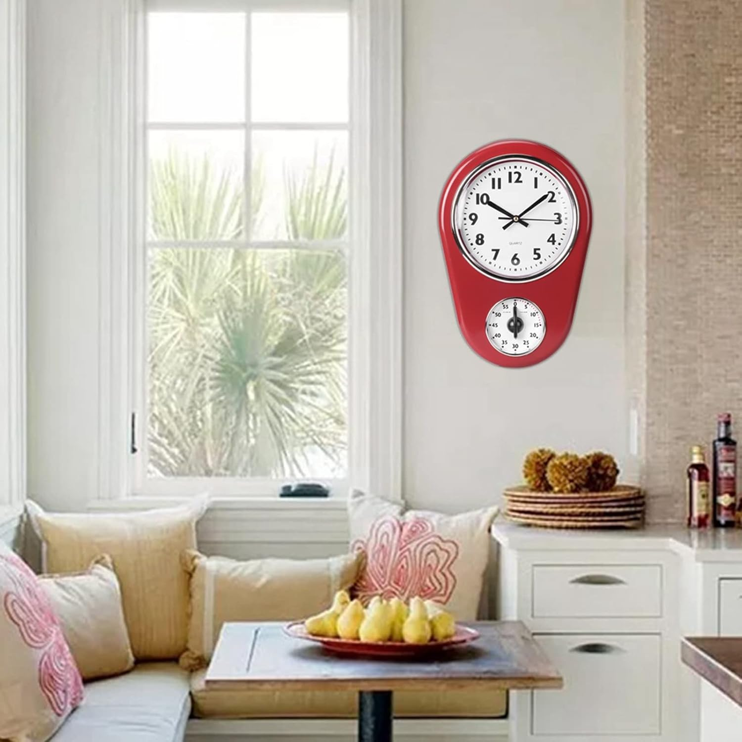 Eine rote Wanduhr mit integriertem Timer hängt über einer Sitzecke und einem Tisch in einem hellen Zimmer.