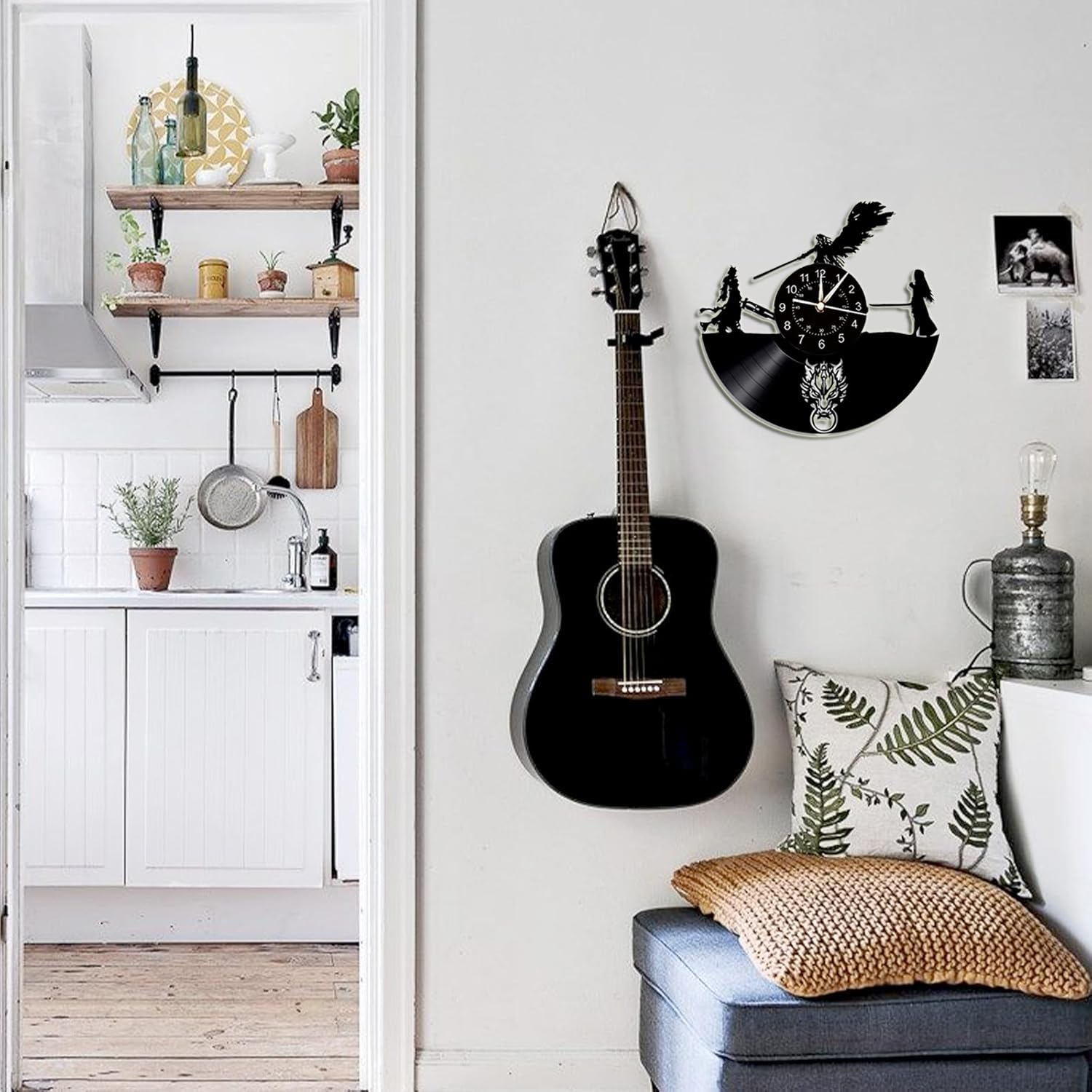 Wohnzimmer mit schwarzer Gitarre, Vinyl-Uhr an weißer Wand und Blick in die Küche.