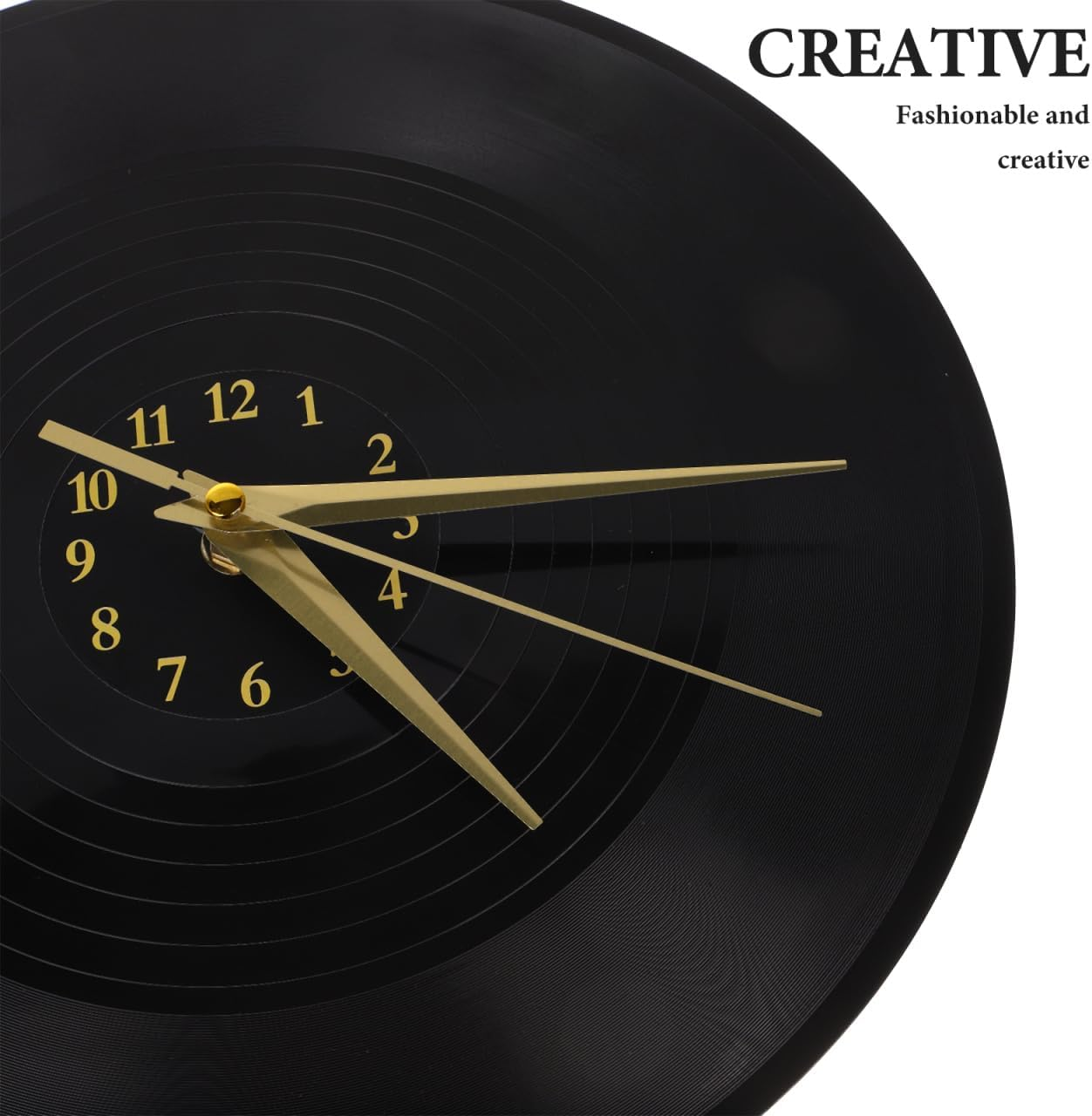 Eine schwarze Wanduhr im Vinyl-Schallplatten-Design mit goldenen Zeigern und Ziffern auf weißem Hintergrund.