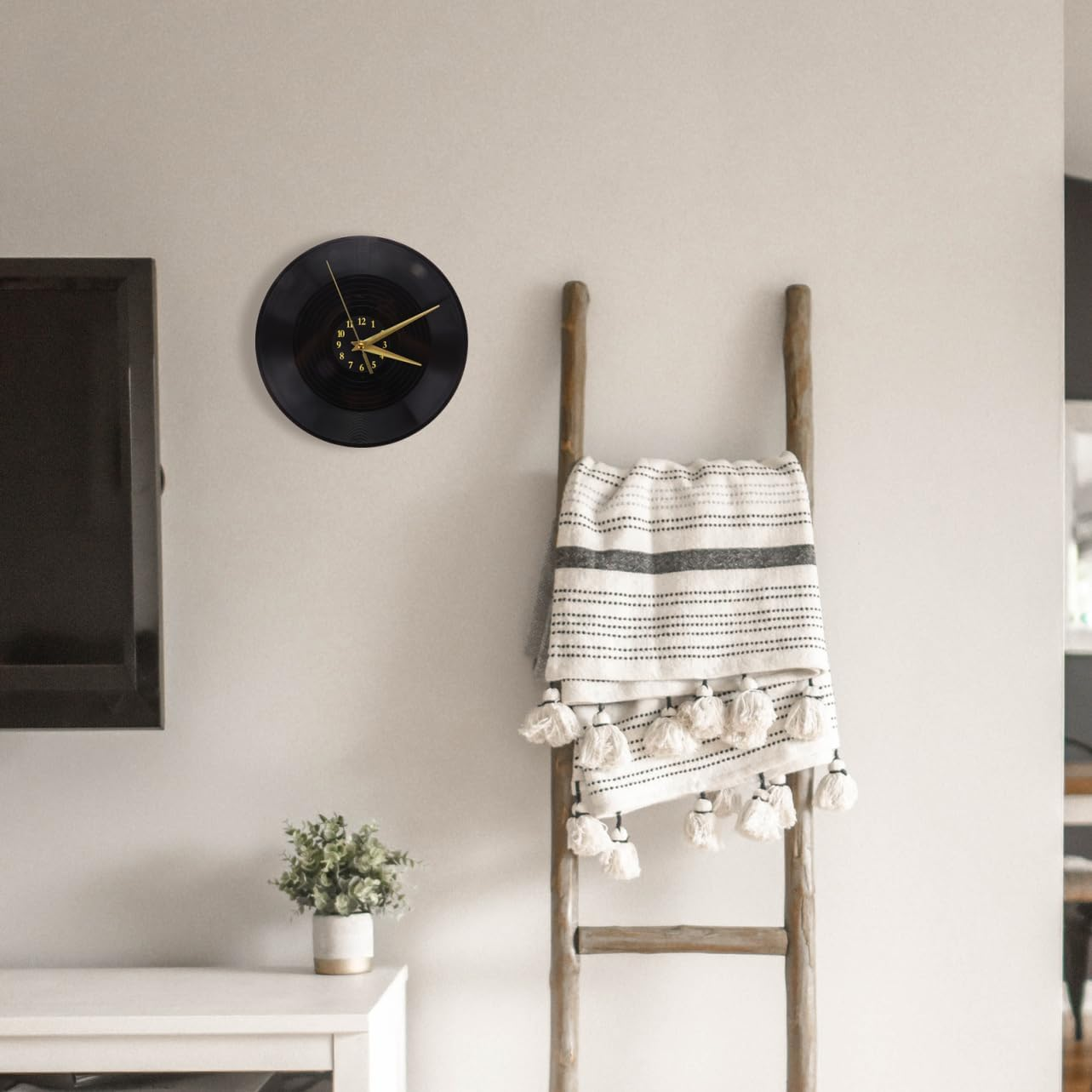 Eine Wanduhr aus einer schwarzen Schallplatte hängt über einem Holztag mit Decke.