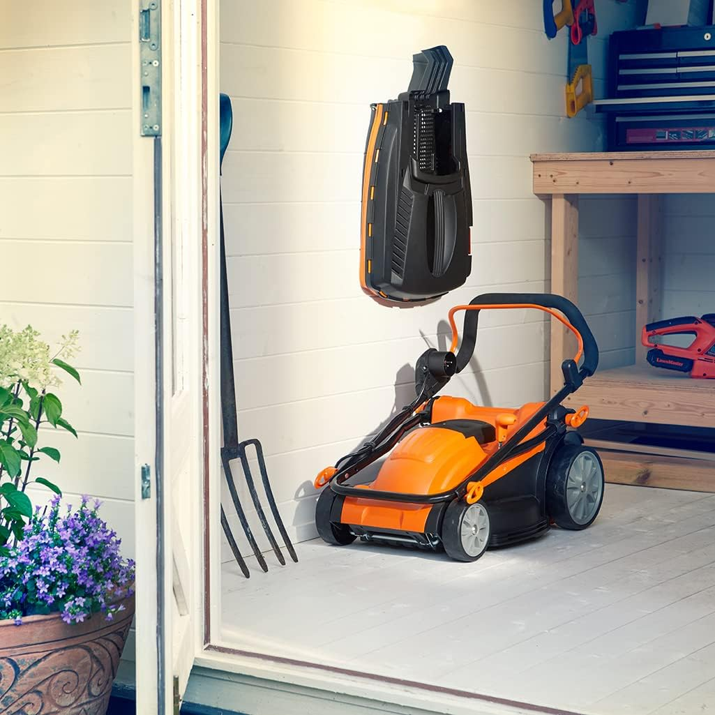 Ein orange-schwarzer Rasenmäher und ein Wandhalter in einem hellen Schuppen mit Holzregal und Werkzeugen.