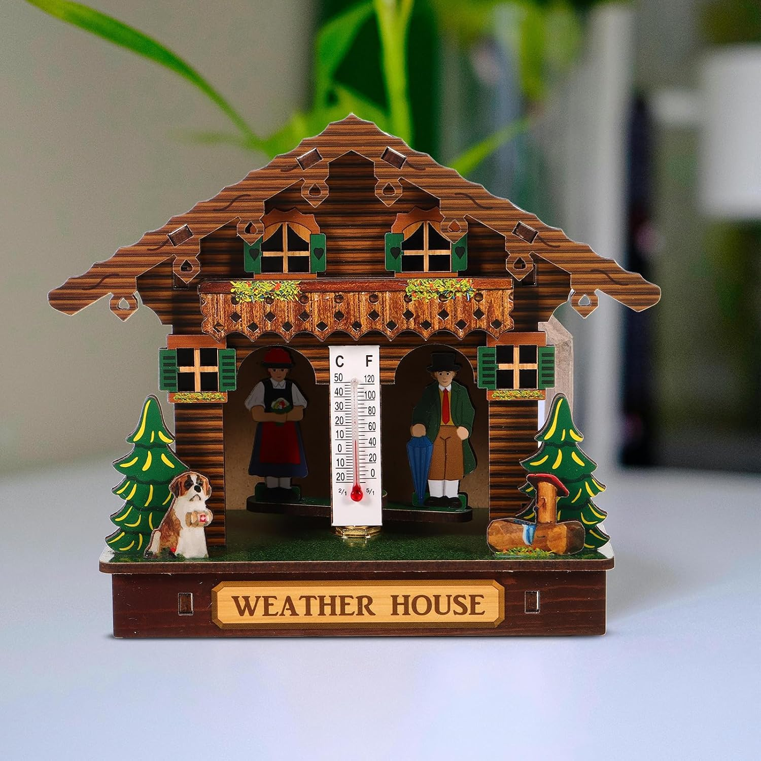 Ein hölzernes Wetterhäuschen mit Figuren von Mann, Frau und Hund sowie einem Thermometer in der Mitte.
